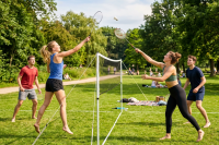 Two women and two men playing badminton on grass with a net between them